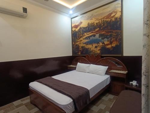 a bedroom with a bed with a painting on the wall at Bin-Umar Guest House chakswari in Burotiān