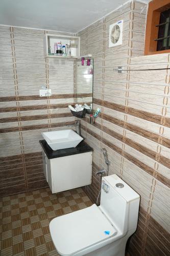 a bathroom with a white toilet and a sink at Kaivalyam Homestay in Wayanad