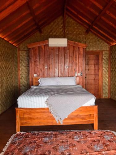 a bedroom with a bed in a wooden room at Anorawi Supersuck Surf Accommodation in Maluk