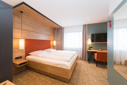 a bedroom with a bed and a desk and a television at Schneider HOTEL & APARTMENTS ALLERSBERG in Allersberg