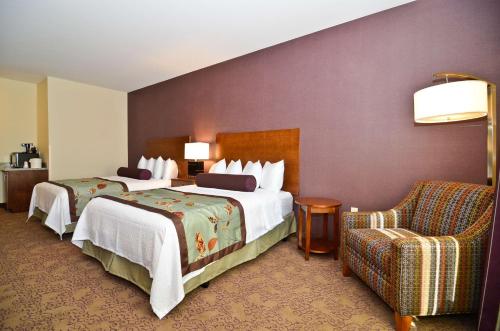 a hotel room with two beds and a chair at Best Western Plus Carousel Inn & Suites Burlington in Burlington