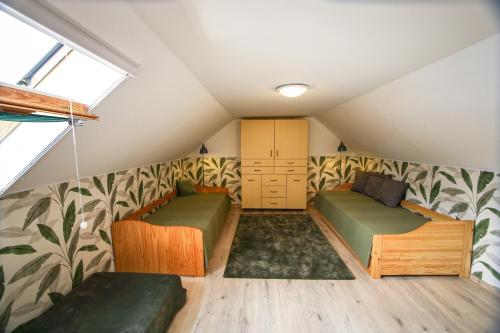 a attic bedroom with two beds and a window at Bambuszkert in Kisoroszi