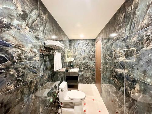 a bathroom with a toilet and a marble wall at Vera Luxury Hotel in Hanoi
