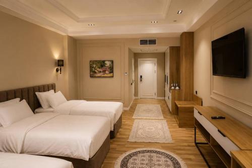 a hotel room with two beds and a flat screen tv at Amanat Prestige Hotel in Samarkand