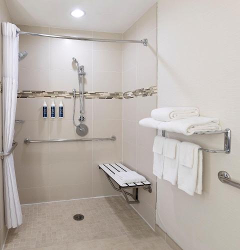a bathroom with a shower and white towels at Redondo Beach Hotel, Tapestry Collection by Hilton in Redondo Beach