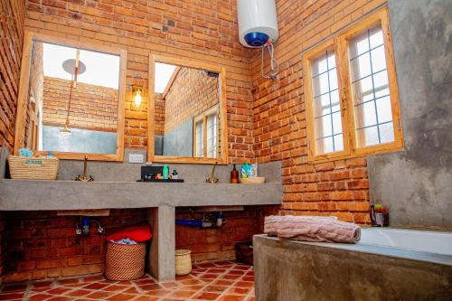 a brick bathroom with a sink and a bath tub at Tranquil Hillhouse in Nkoanrua