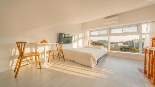 a bedroom with a bed and a table and a window at Geoje Forest-Morning Spa Pension in Geoje
