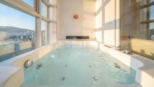 a jacuzzi tub in a room with a large window at Geoje Forest-Morning Spa Pension in Geoje