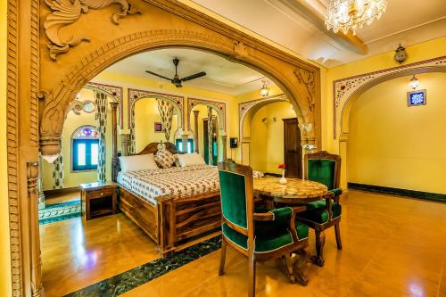 an ornate bedroom with a bed and a table at Alivaa Heritage Lotwara Fort - Near Shri Mehandipur Balaji Temple in Dausa