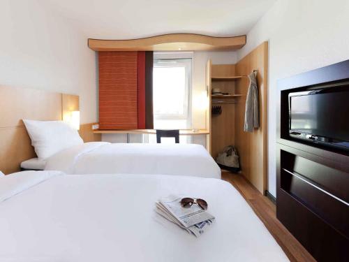 a hotel room with two beds and a flat screen tv at ibis München City Süd in Munich