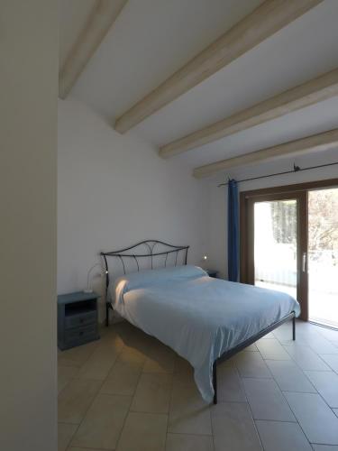 a bed in a white room with a large window at La Corte Degli Ulivi Appartamenti in Cala Liberotto