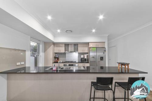 a kitchen with a counter and stools in a room at Spacious 4BR Yard Retreat in Kellyville