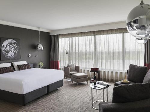 a hotel room with a bed and a living room at Pullman Melbourne Albert Park in Melbourne