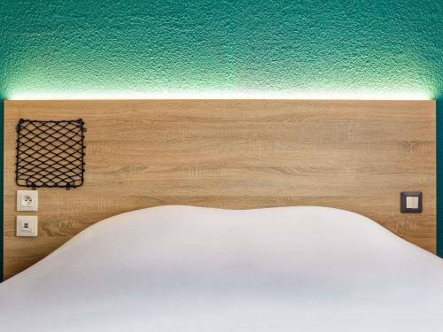 a bed with a wooden headboard and a green wall at HôtelF1 Angoulême in Champniers