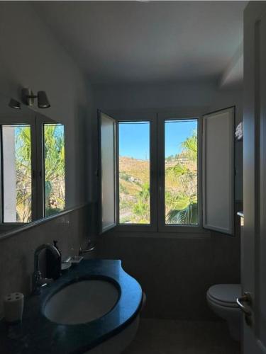 a bathroom with a sink and a toilet and windows at Kento Resort Hotel in Centuripe