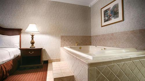 ein Hotelzimmer mit einer Badewanne und einem Bett in der Unterkunft Best Western Wilderness Trail Inn in Barbourville