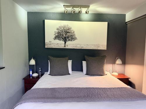 a bedroom with a bed with a tree on the wall at Seldom Seen in Malelane