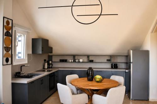 a kitchen with a wooden table and white chairs at Luminosa Collection - Casa Celeste in Razáta
