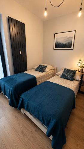 a bedroom with two beds with blue sheets on them at Nad Jeziorem dla przyjaciół Apartament in Serock