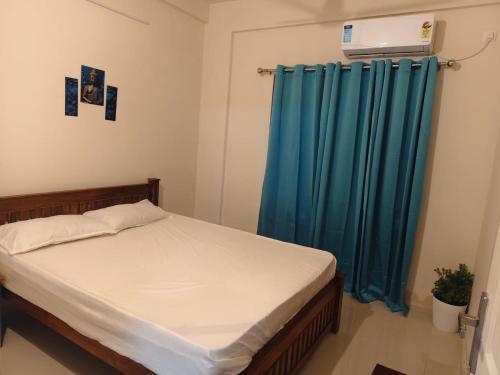 a bedroom with a bed and a blue curtain at Govindha bhavanam 150 meters from Guruvayur temple in Guruvāyūr