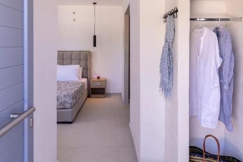 a bedroom with a bed and a door with a closet at Chrysonisos Suites with Sunset & Seaviews near Kini in Ano Syros