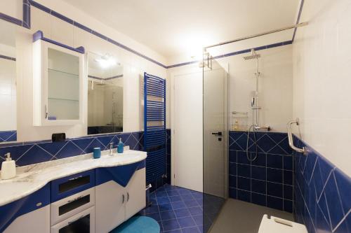 a blue bathroom with a sink and a shower at Appartamento Maison Sabrina con vista giardino in Borgofranco dʼIvrea