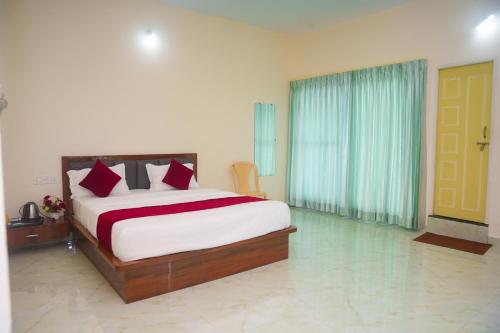 a bedroom with a large bed with red pillows at D D Luxury Inn in Chikmagalūr