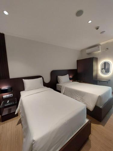 a hotel room with two beds and a mirror at Hotel Imam Bonjol by Benhas in Padang
