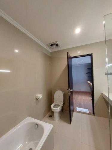 a bathroom with a toilet and a bath tub at Hotel Imam Bonjol by Benhas in Padang