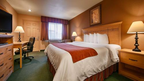 SutherlinにあるBEST WESTERN PLUS Hartford Lodgeの大きなベッドとデスクが備わるホテルルームです。