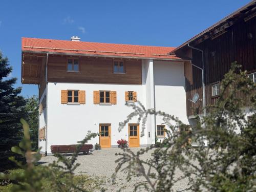 a white building with orange doors and a brown roof at Ferienhof Winkler in Bernbeuren