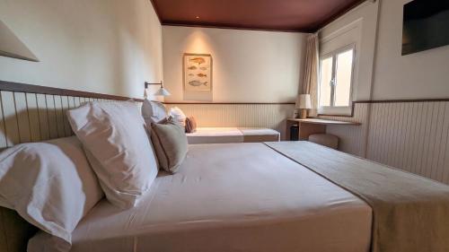 a bedroom with a large white bed and a window at Hotel Medium Montecarlo in Llafranc