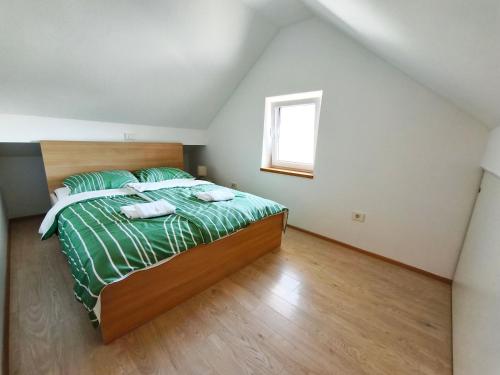 a bedroom with a bed with green sheets and a window at Apartment Cankar's View in Vrhnika