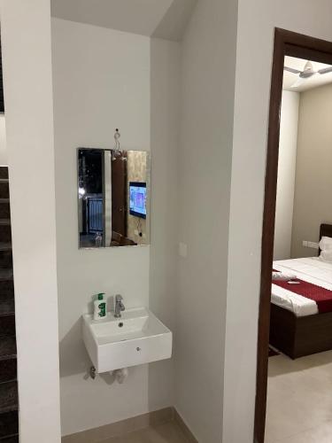 a white bathroom with a sink and a bed at coastal coral in Tirupporūr