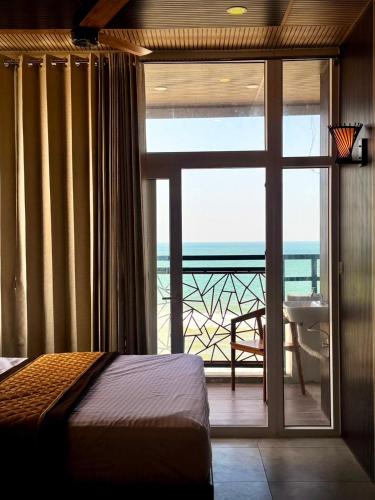 a bedroom with a sliding glass door with a view of the ocean at Serenity Beach Inn in Pondicherry