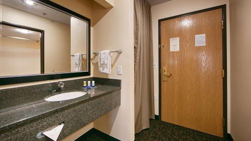 a bathroom with a sink and a mirror and a door at Best Western Plus - Wendover Inn in Wendover