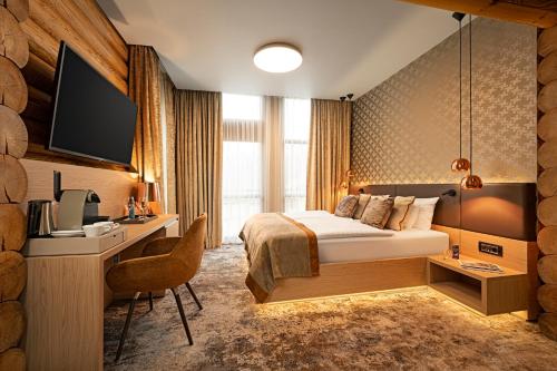 a hotel room with a bed and a desk and a tv at Avalon Resort & SPA in Miskolctapolca