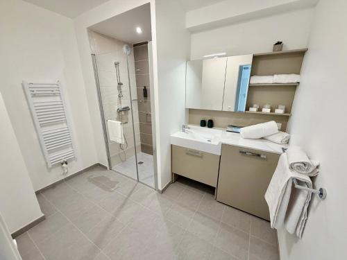 a white bathroom with a shower and a sink at DOMITYS - Les Cerfs-Volants in Berck-sur-Mer