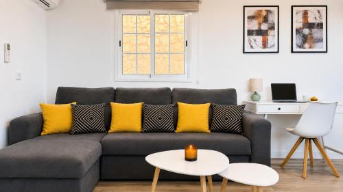 a living room with a gray couch with yellow pillows at JVG VILLAS - Villa Valeria in Güimar