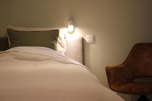 a bedroom with a bed and a lamp and a chair at Het Plategoed in Oosthoek