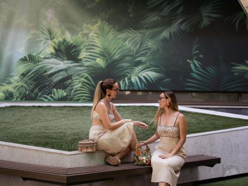 two women in dresses sitting on a bench at Novotel Madrid Center in Madrid