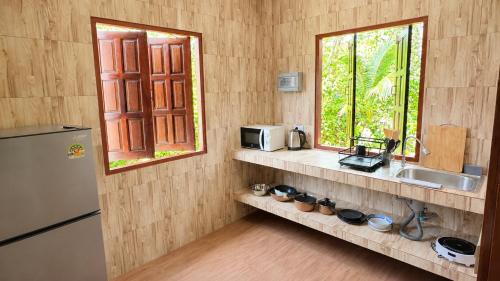 a kitchen with a sink and a microwave and a window at Zen Village in Ko Phangan