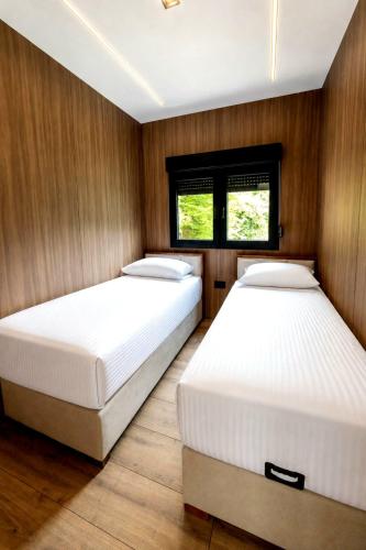 two beds in a room with wood paneling at Perućac Lake Residence in Miličevići