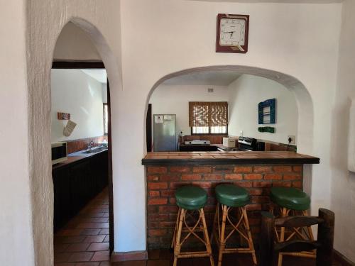 a bar in a kitchen with two green stools at Peter Pan Place in Port Edward