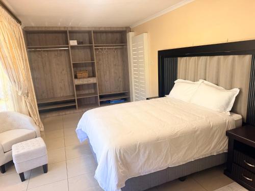 a bedroom with a large white bed and a chair at The Cozy Corner House in Durban