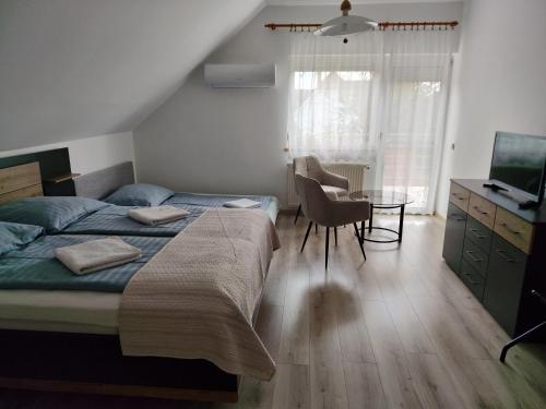 a bedroom with a bed and a table and a television at Abigel Thermal Apartman in Bük