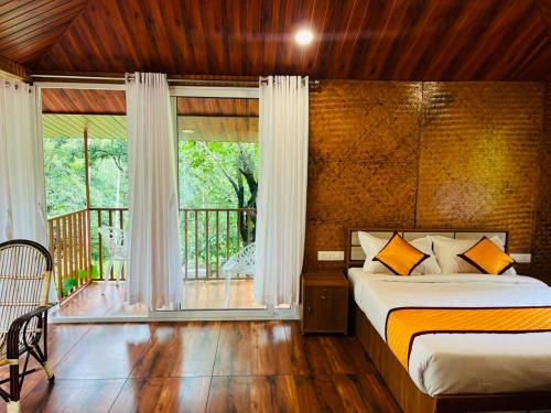 a bedroom with a bed and a balcony at Cave Valley Wayanad in Ambalavayal