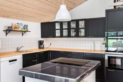 a kitchen with black cabinets and a counter top at Coastal Hideout Vacation Home in Bøtø By