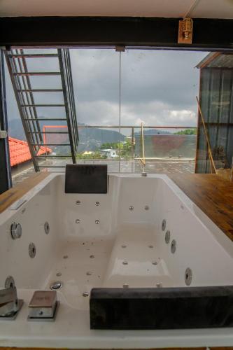a large white bath tub in a room with a large window at Luxe Vista Resort Kodai in Kodaikānāl