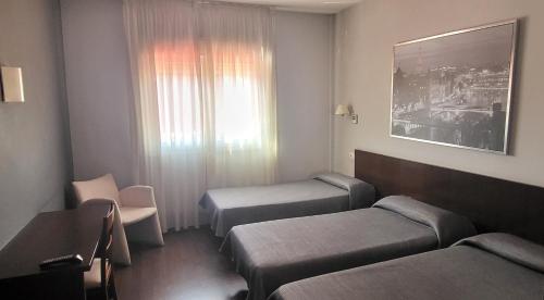 ein Hotelzimmer mit zwei Betten und einem Fenster in der Unterkunft Hostal T4 in Paracuellos de Jarama